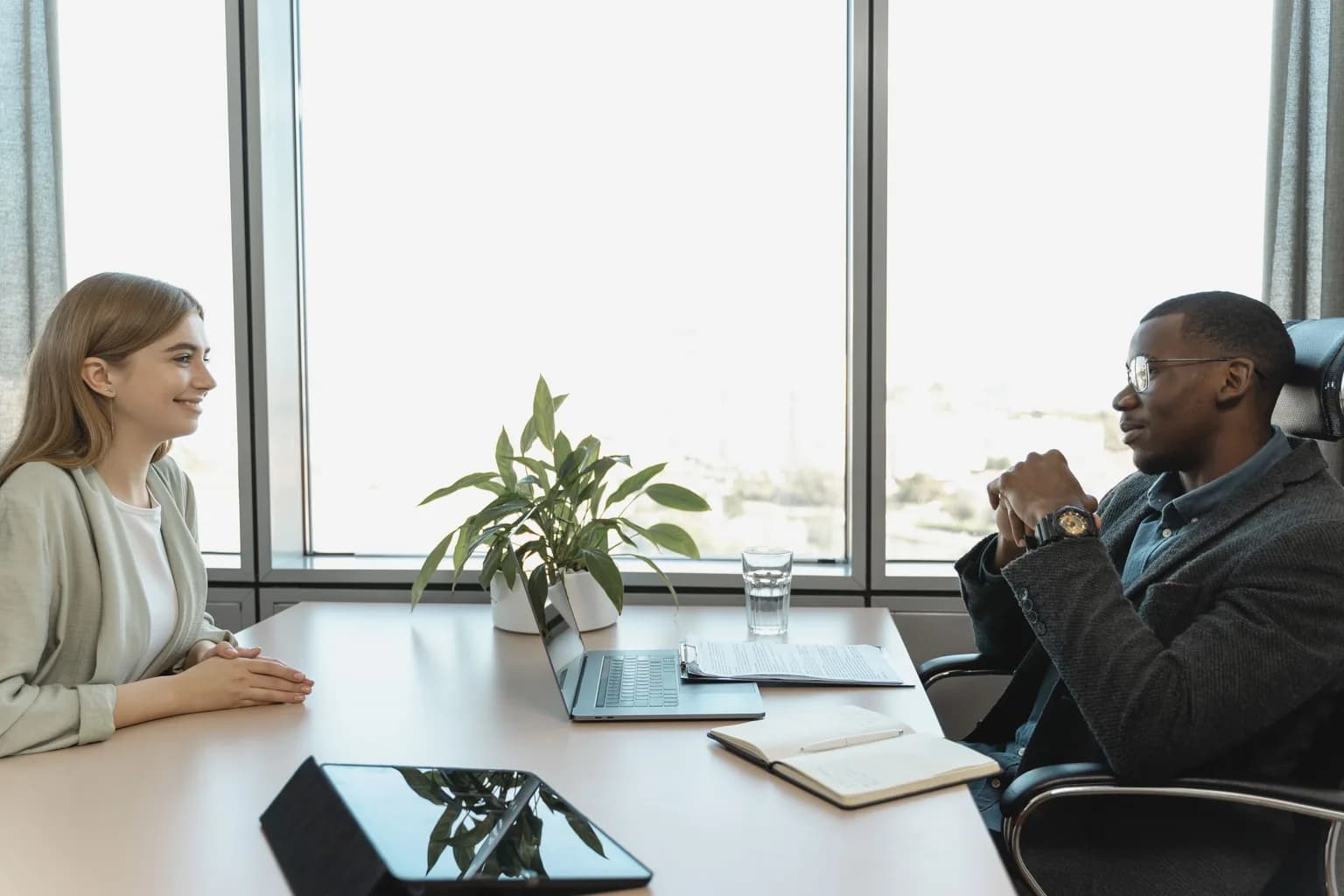 A hiring manager holding a one-on-one interview with a candidate across an office desk