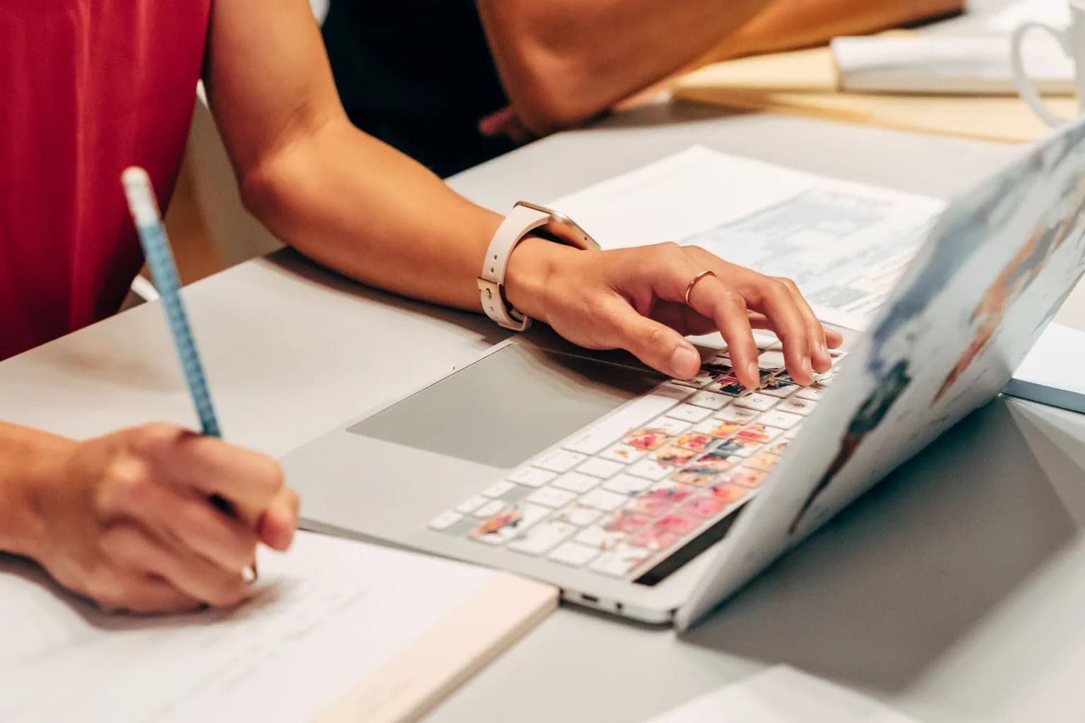 A marketing assistant coordinating content plans between a laptop and handwritten notes